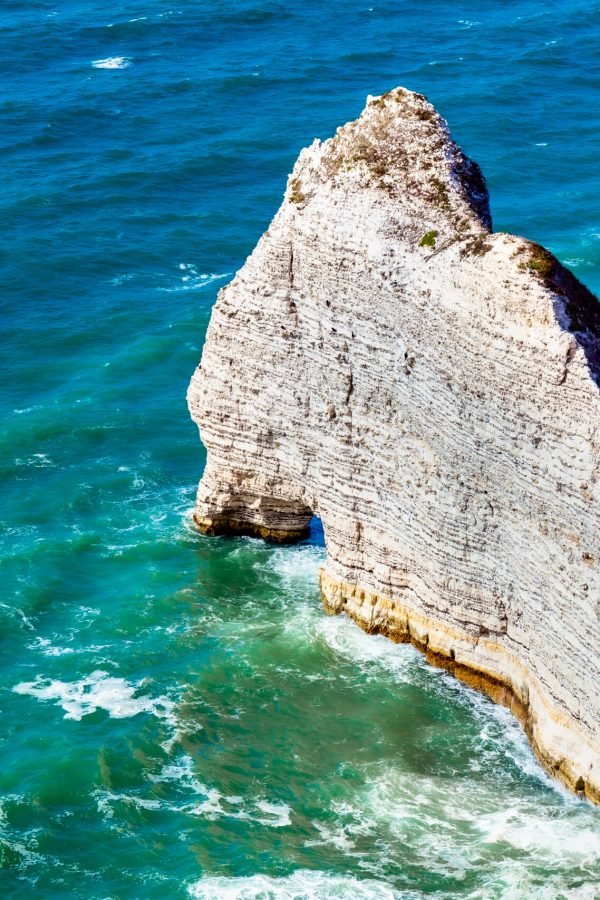 Etretat Aval cliff, rocks and natural arch landmark and blue ocean. Normandy, France, Europe.