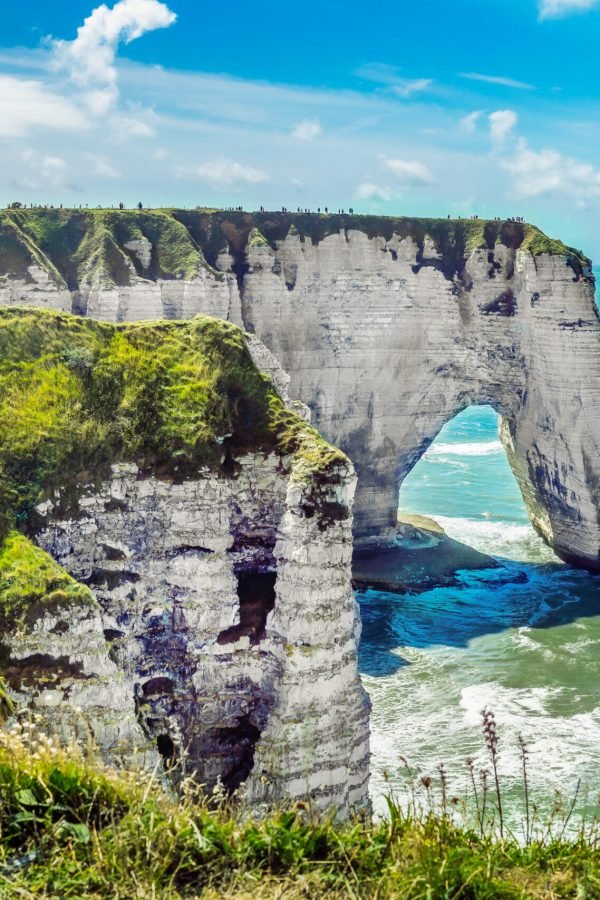 Etretat Aval cliff, rocks and natural arch landmark and blue ocean. Normandy, France, Europe.